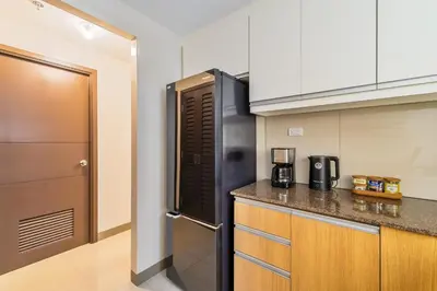 a kitchen with a black refrigerator and a counter at Ocean View Condo with Infinity Pool, Gym, Spa - Next to Okada, Solaire & MOA in Manila