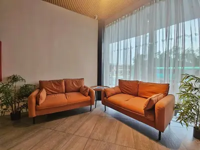 two orange leather couches in a room with a large window at Terra Hotel Kawit in Kawit