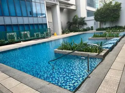 a large blue swimming pool in front of a building at LUXESTAYSMNL STYLISH FAMILY 2BR SUITE POOLGYM 400MBPS WIFI NETFLX Amazing City View in Manila