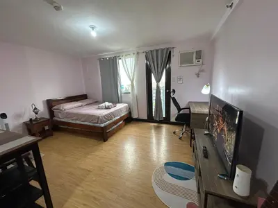 a living room with a bed and a television at Solstay in Manila