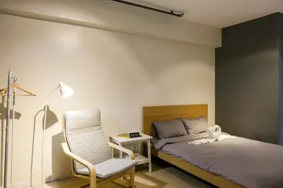 a bedroom with a bed and a chair and a table at Siesta Spaces Adela in Manila