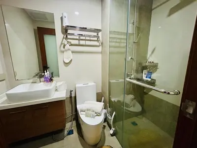 a bathroom with a shower and a toilet and a sink at Cozy 1BR with BGC View Gym and Pool Included in Manila