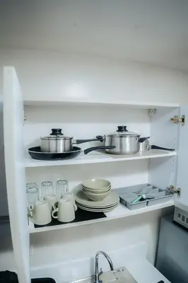 a kitchen shelf with pots and pans and dishes at The House of Five - Brand New Hotel Style Condo in Manila