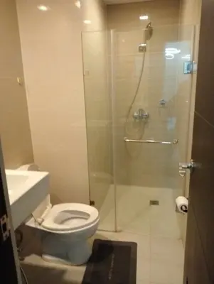 a bathroom with a shower with a toilet and a sink at Newport 101 - East Wing in Manila