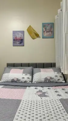 a bedroom with a bed and two pictures on the wall at Cozy Studio Condo Unit at Fullerton Suites in Silang