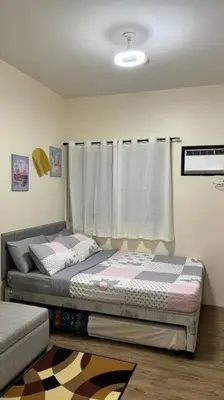 a bedroom with a bed and a window with curtains at Cozy Studio Condo Unit at Fullerton Suites in Silang