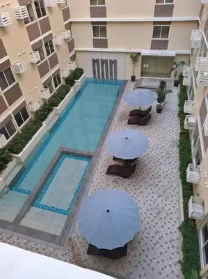 an overhead view of a swimming pool with two blue umbrellas at Cozy Studio Condo Unit at Fullerton Suites in Silang