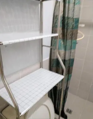 a white shelf next to a toilet in a bathroom at Royal loft with breakfast options in Cainta