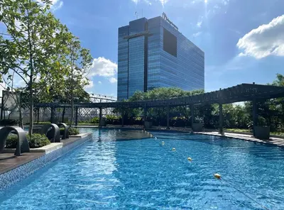 a swimming pool in front of a tall building at Cozy 1 BR San Lorenzo Place Netflix 4KM NAIA in Manila