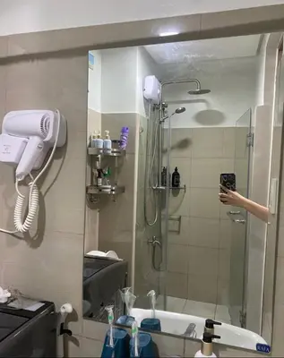 a person taking a picture of a shower in a bathroom at E & R Staycation Condotel near Mall of Asia in Manila