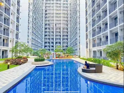 a person sitting in a chair in front of a large building at E & R Staycation Condotel near Mall of Asia in Manila