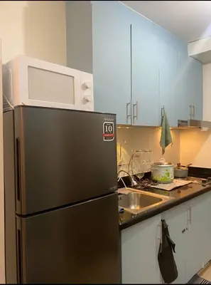 a kitchen with a refrigerator and a microwave on top of it at E & R Staycation Condotel near Mall of Asia in Manila