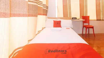 a bed in a room with a redbrother bedspread on it at RedDoorz at Prince Hotel near NAIA T1 in Manila