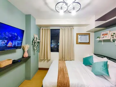 a bedroom with a large bed and a flat screen tv at 1BR Condotel Ridgewood Towers Taguig City #RW06 in Manila