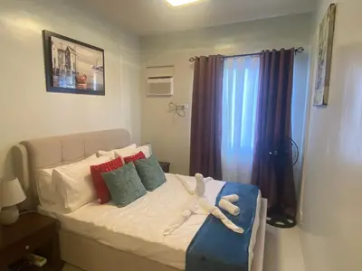 a bed with a stuffed animal on it in a bedroom at Kral Suite in Las Piñas in Manila