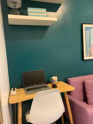 a laptop sitting on a wooden table next to a chair at Your Happy Home in Mall of Asia in Manila