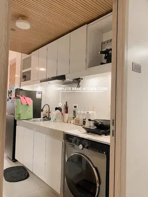 a kitchen with white cabinets and a washer at Beans Crib Staycation at SMDC Green 2 Residences in Dasmariñas