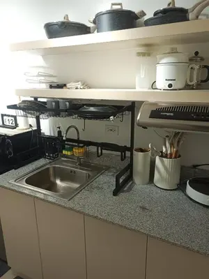 a kitchen counter with a sink and a shelf with pots and pans at La Maison d'Antoine in Manila