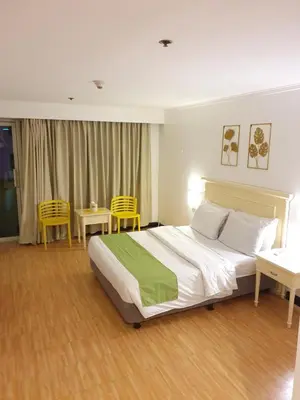 a bedroom with a bed and two tables and chairs at Travel time suites bel air soho in Manila