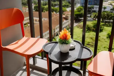 a table and two chairs and a vase with flowers on a balcony at Oranje Suite near NAIA AIRPORT in Manila