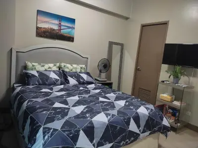 a bedroom with a blue and white comforter on a bed at LDN Secret Crib PALM TREE Across NAIA T3 in Manila