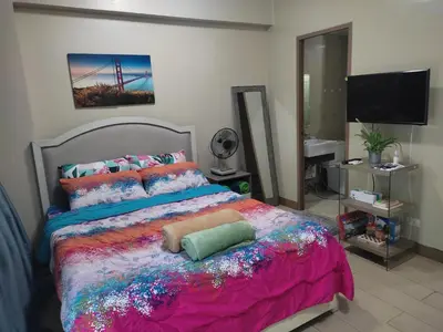 a bedroom with a large bed with a colorful bedspread at LDN Secret Crib PALM TREE Across NAIA T3 in Manila