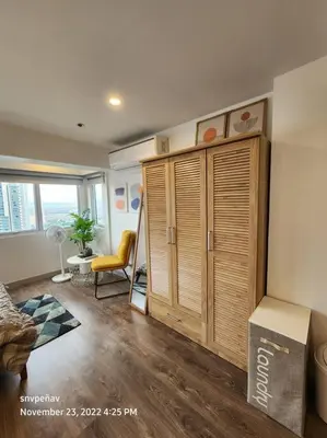 a living room with a large wooden cabinet at Fort Victoria Tower B Condo BGC, Taguig City in Manila
