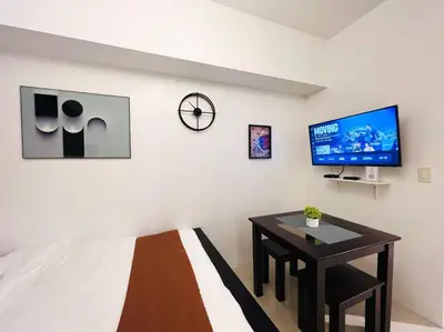 a bedroom with a bed and a table and a tv at 1BR Condotel with Balcony at SM Light Residences #LT01 in Manila