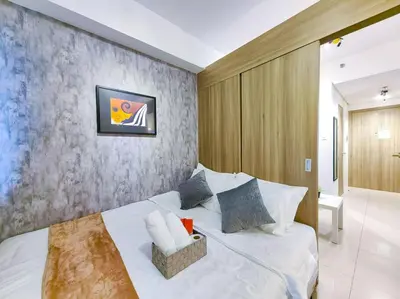 a bedroom with a white bed and a wall at 1BR Condotel with Balcony at FAME Residences #FM03 in Manila