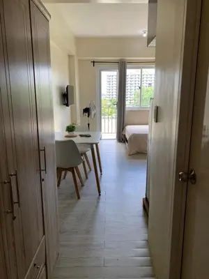a hallway with a room with a table and a bedroom at Studio-type Apartment near Manila International Airport in Manila
