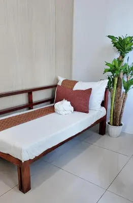 a wooden bench with white pillows and a plant at NITO Modern Philippine Styled Home at Jazz Residences Makati in Manila