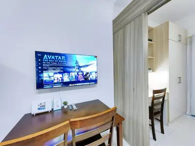 a dining room with a table and a tv on the wall at 1BR Condotel with Balcony at FAME Residences #FM06 in Manila