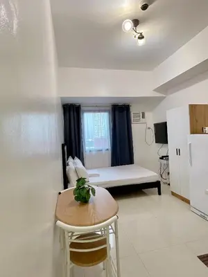 a small room with a bed and a table at Serene Condo Unit in Front of US Embassy in Manila