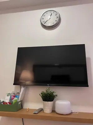 a clock on a wall above a television on a shelf at Casa Del Castillo at Fame Residences near Megamall in Manila