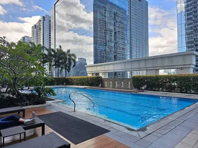 a woman laying on a bench next to a swimming pool at The Infinity Towers in BGC - Spectacular 2BR near Hight Street in Manila