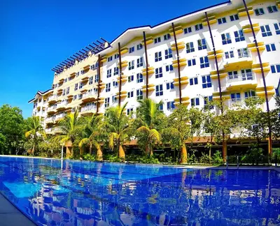 a large building with palm trees in front of a swimming pool at The Rochester, Bridgeview Tower - 1BR Apartment in Manila