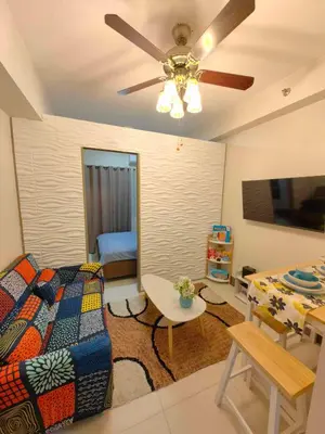 a living room with a bed and a ceiling fan at Casa Fama - Fame Residences Staycation in Manila