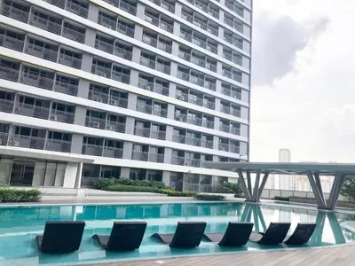 a hotel swimming pool with chairs in front of a building at Casa Fama - Fame Residences Staycation in Manila