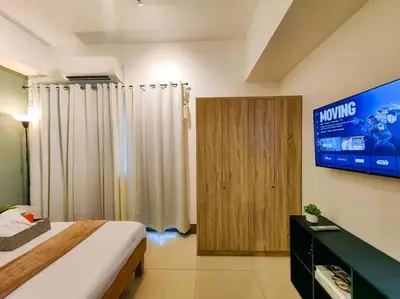 a bedroom with a bed and a tv in a room at 1BR Condotel with Balcony at FAME Residences #FM11 in Manila