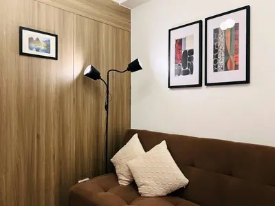 a living room with a brown couch and a lamp at 1BR Condotel with Balcony at FAME Residences #FM12 in Manila