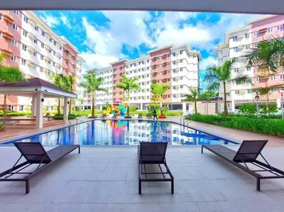 a swimming pool with two chairs and buildings at Jasrich Suite Behind SM trece martires HOPE RESIDENCES SMDC in Cavite