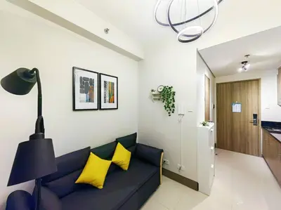 a living room with a blue couch and yellow pillows at 1BR Condotel with Balcony FAME Residences #FM24 in Manila