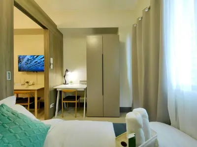 a bedroom with a bed and a desk and a table at 1BR Condotel with Balcony FAME Residences #FM24 in Manila