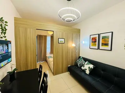 a living room with a couch and a table and a bed at 1BR Condotel with Balcony at FAME Residences #FM41 in Manila
