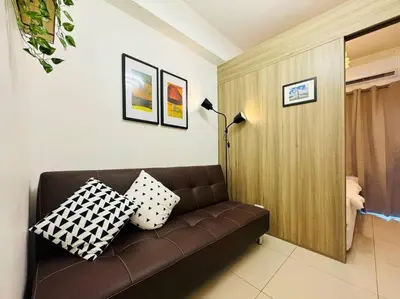 a brown couch in a living room with pillows on it at 1BR Condotel with Balcony at FAME Residences #FM42 in Manila