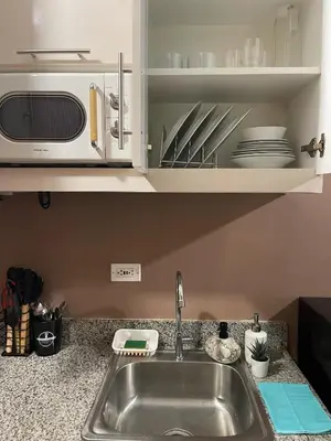 a kitchen counter with a sink and a microwave at SPRING RESIDENCES - 2BR Condo near Airport with balcony and pool views in Manila