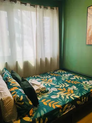 a bedroom with a bed with a flowered blanket and a window at SPRING RESIDENCES - 2BR Condo near Airport with balcony and pool views in Manila