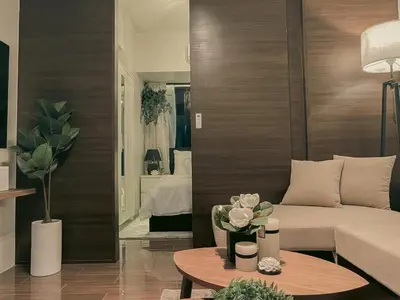 a living room with a bed and a table with flowers at The Skyline Oasis Makati in Manila