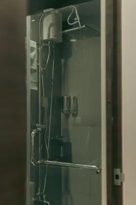 a shower in a bathroom with a mirror at The Skyline Oasis Makati in Manila