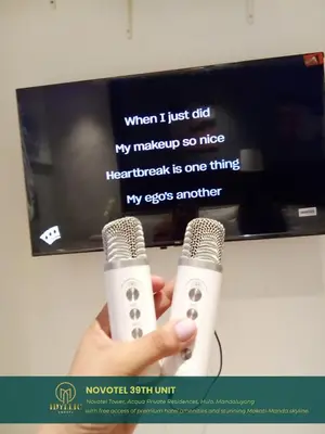 a person holding two microphones in front of a tv at Novotel Twin Bed at Mandaluyong Near Makati FREE pool in Manila
